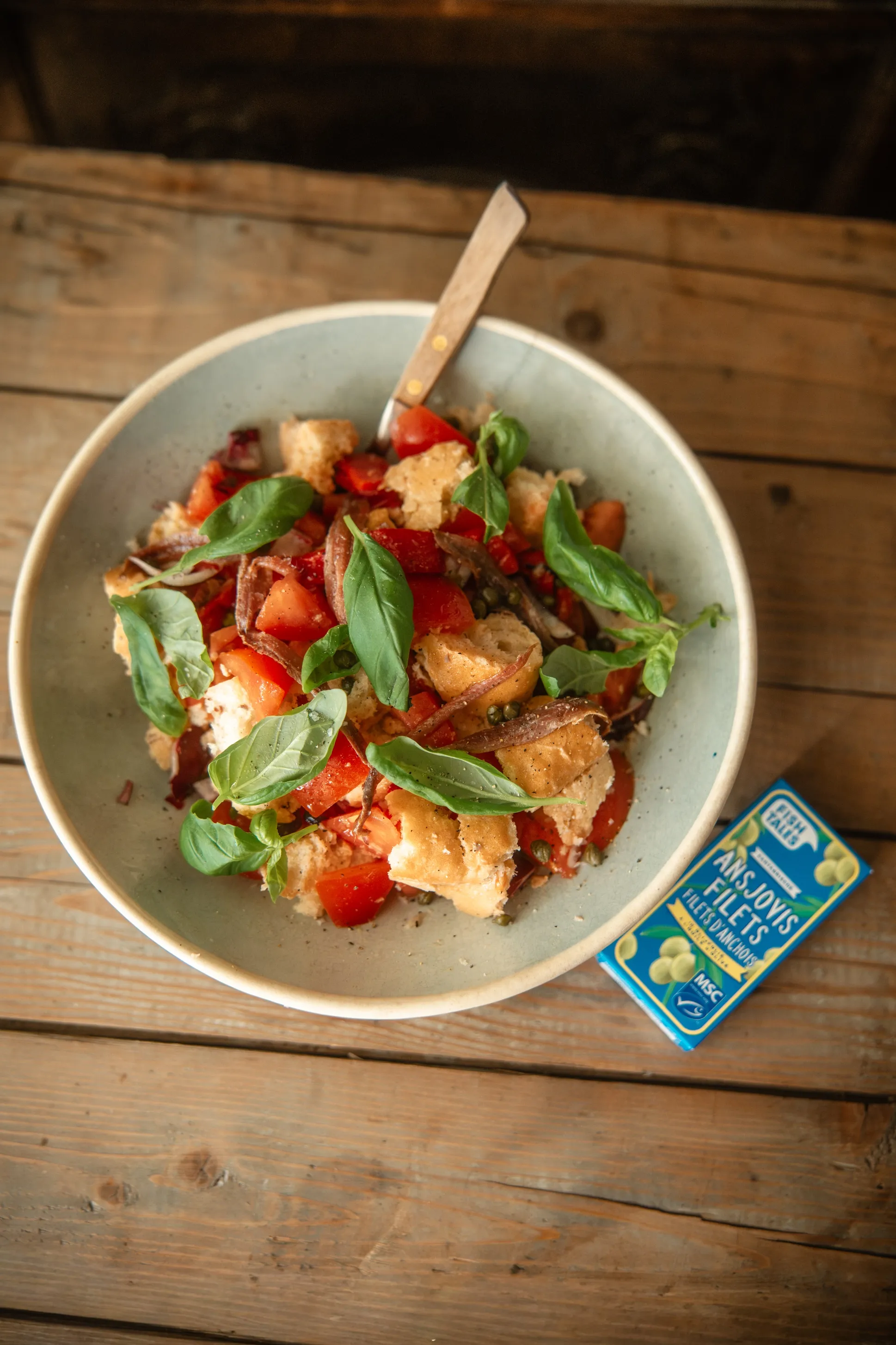 A fresh panzanella salad with toasted bread, ripe tomatoes, and basil in a ceramic bowl.