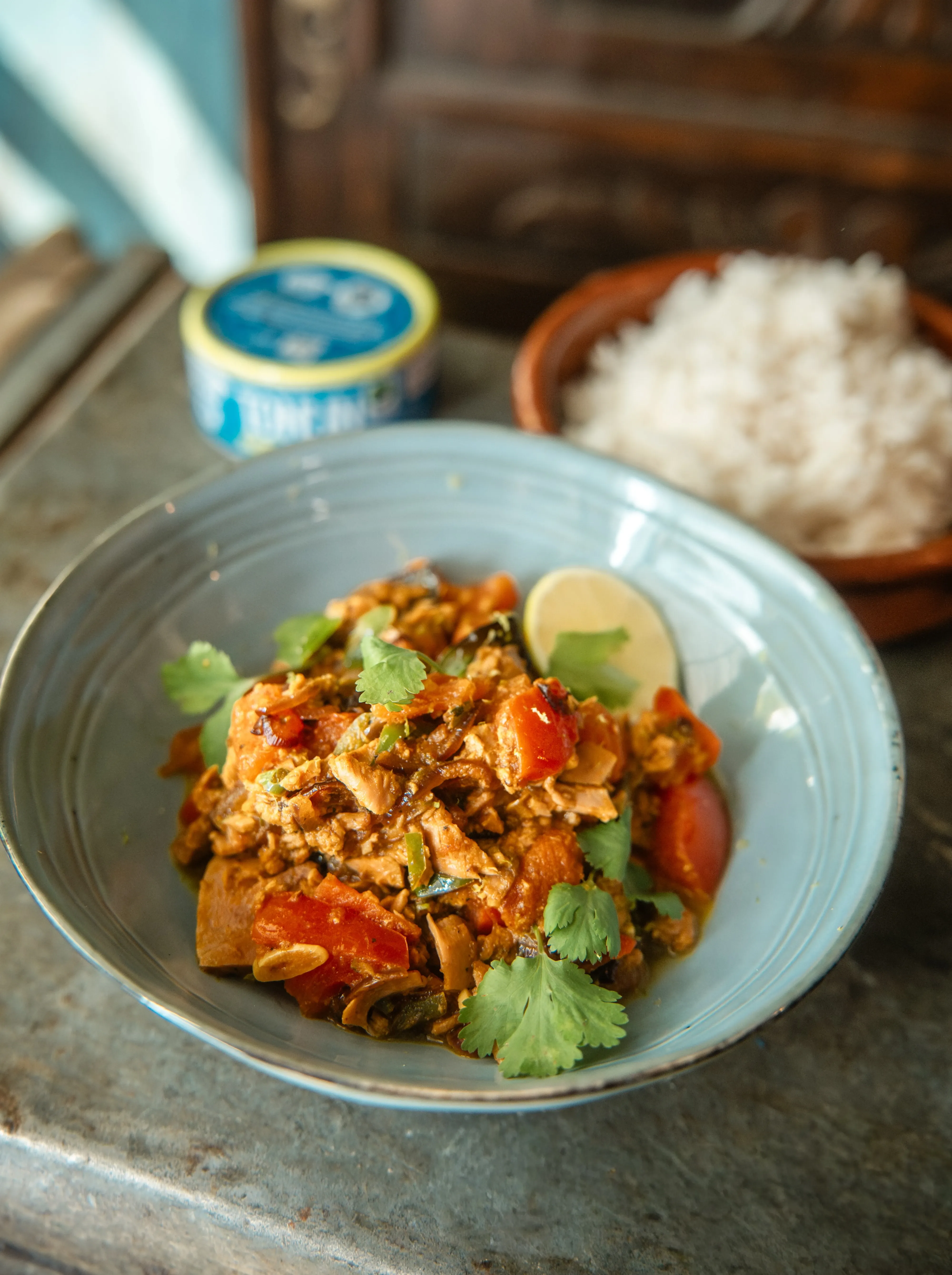 Chicken and tomato curry with cilantro and lime wedge, served with rice.
